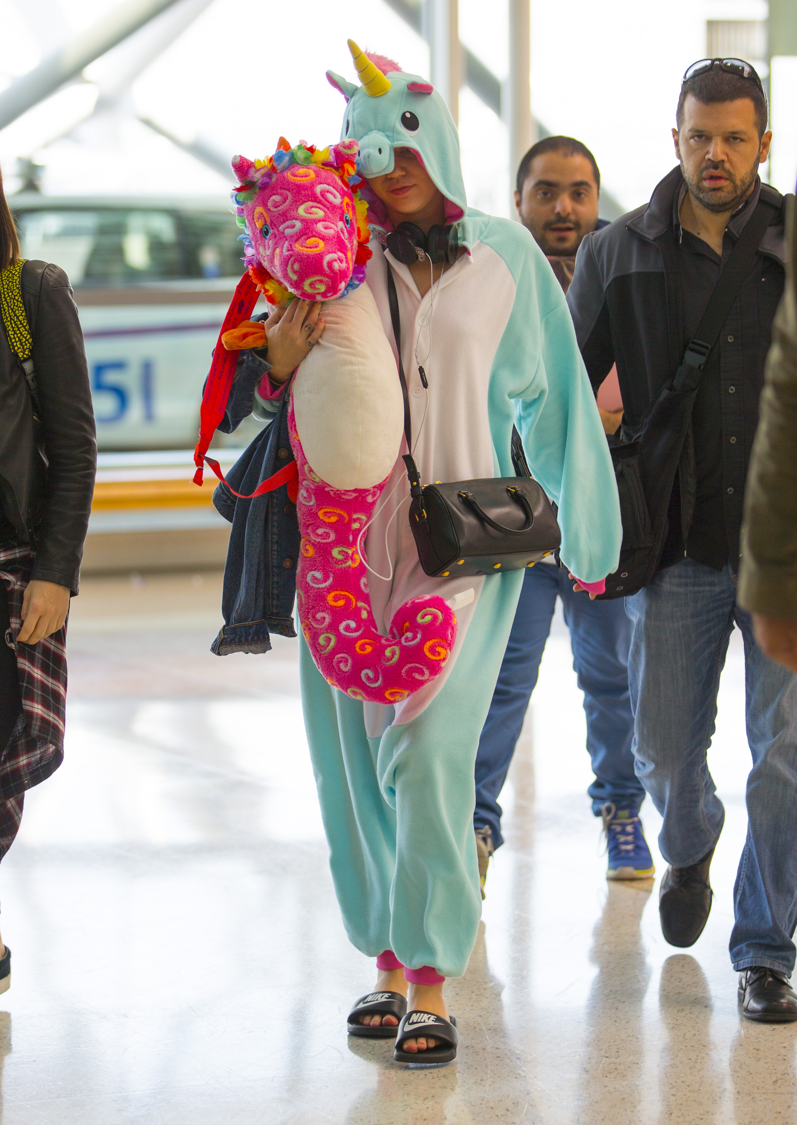 Miley Cyrus wears a Unicorn Onesie and holds a toy unicorn through Sydney Airport