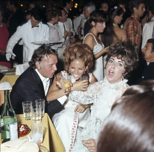 Richard Burton, Elizabeth Taylor and Claudia Cardinale toast together during a party