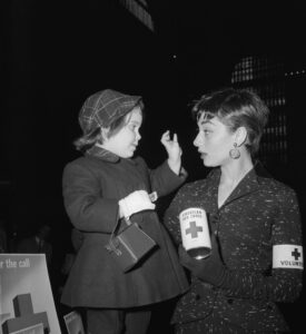 Audrey Hepburn Holding Red Cross Can and Talking With Young Girl