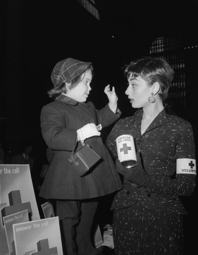 Audrey Hepburn Holding Red Cross Can and Talking With Young Girl
