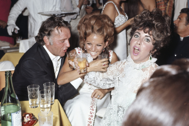 Richard Burton, Elizabeth Taylor and Claudia Cardinale toast together during a party