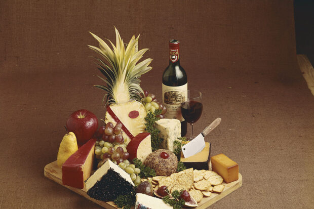 Various cheese, fruits and wine on chopping board
