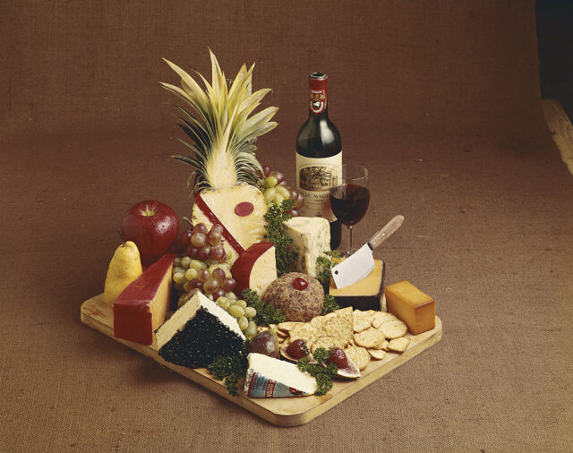 Various cheese, fruits and wine on chopping board