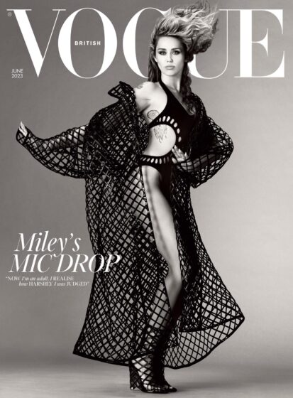 Image shows Miley Cyrus, a white woman, on the cover of British Vogue. The full-length, black and white image captures Miley mid-dance move, wearing an Alaïa bodysuit under a floor-length mesh Alaïa coat, with Alaïa mesh boots that reach to mid-calf. Above her head, the Vogue logo in big white letters. The cover also reads: “Miley’s mic drop.”
