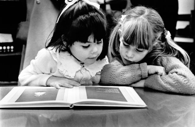 Petites filles lisant un livre dans une bibliothèque à Genève