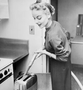 Woman Cleaning Toaster with Vacuum Cleaner