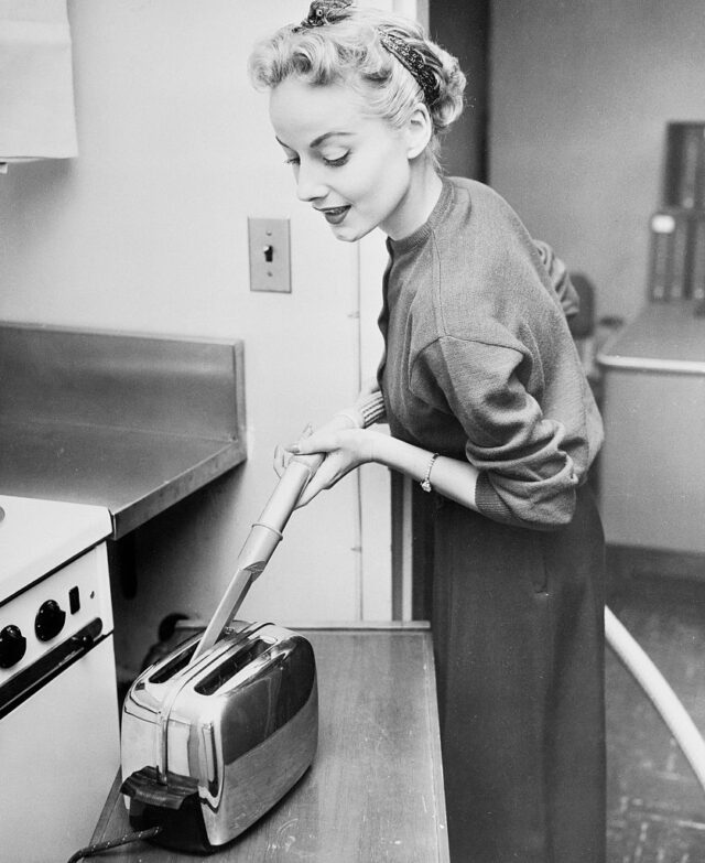 Woman Cleaning Toaster with Vacuum Cleaner